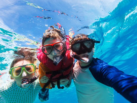 Father and son snorkeling Underwater portrait of family snorkeling together at clear tropical ocean